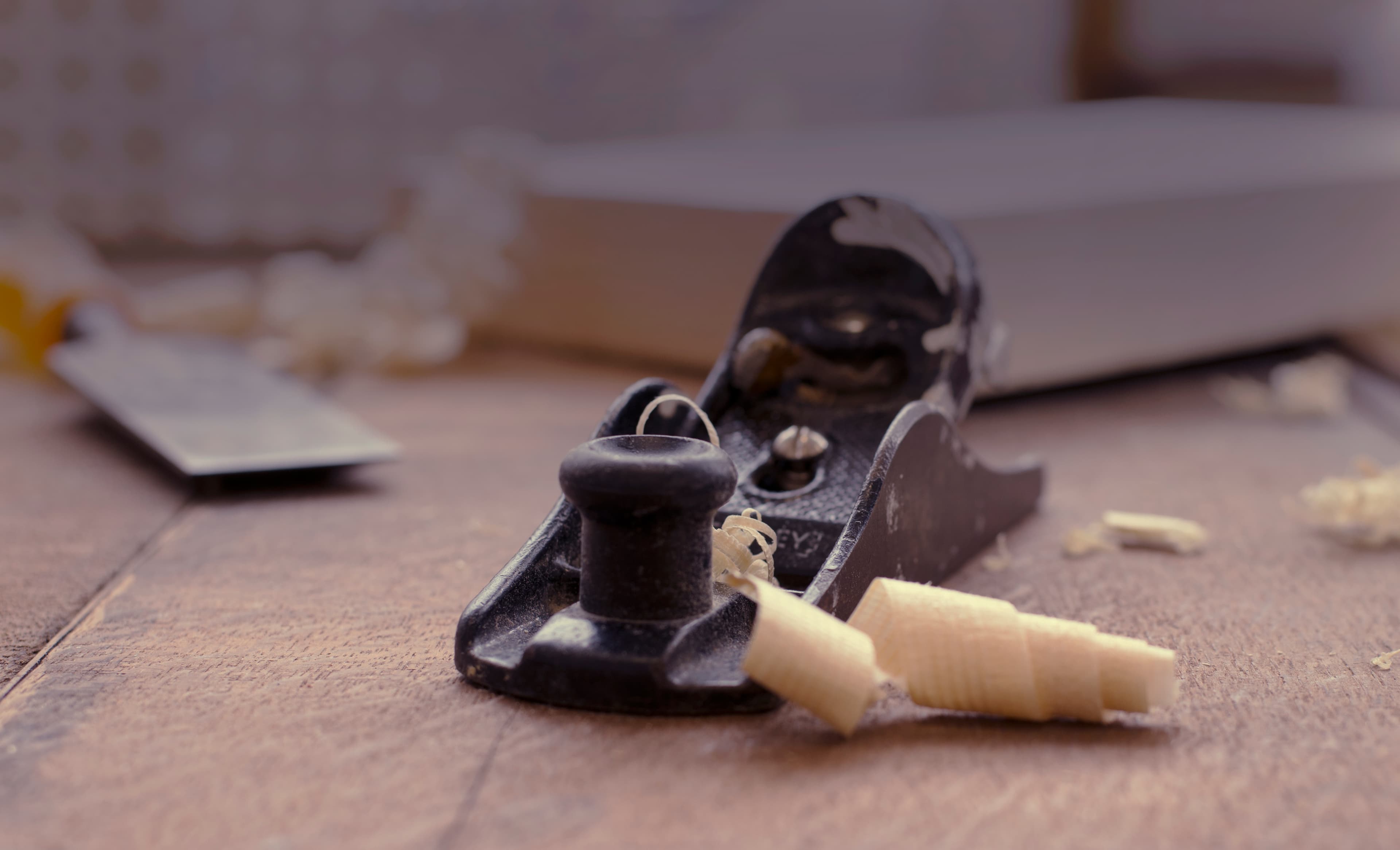 Hand plane curling shavings off a timber board — the bespoke-making process